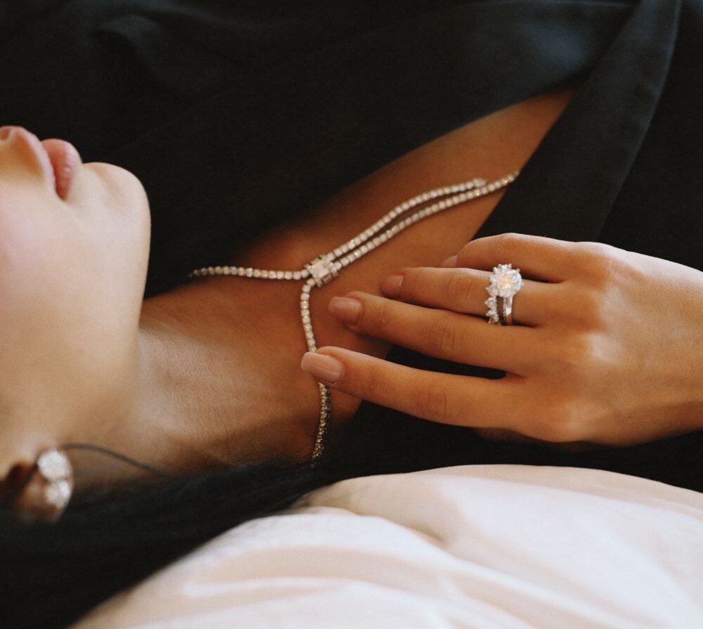 Diamond lariat necklace and solitaire ring resting against the collarbone