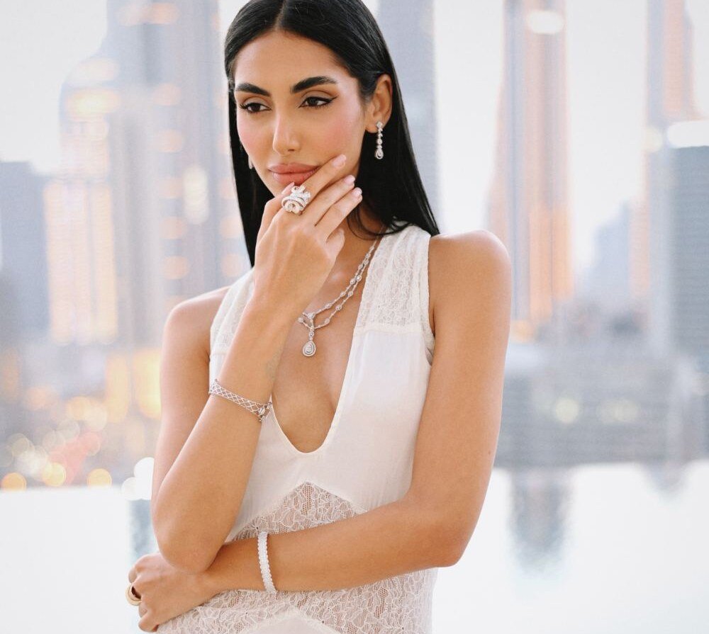 Diamond drop earrings, layered necklace and cocktail ring worn with a hand at the chin