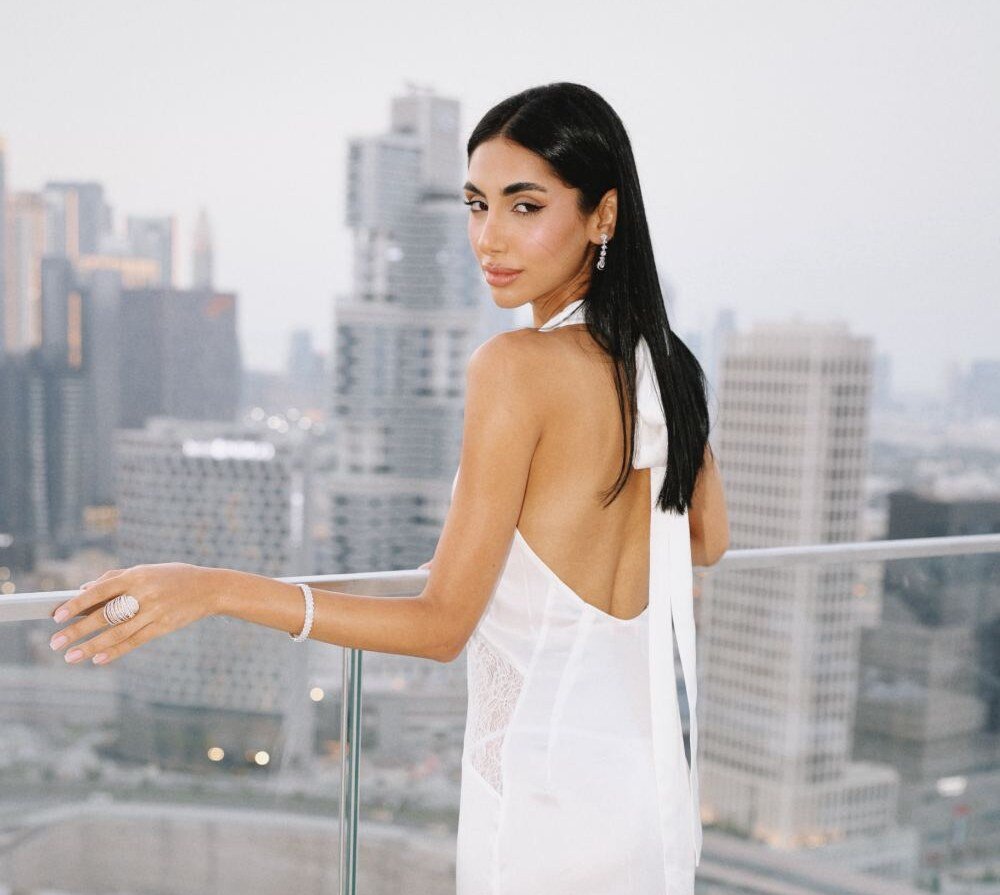 Model in a backless white dress on a terrace overlooking the skyline
