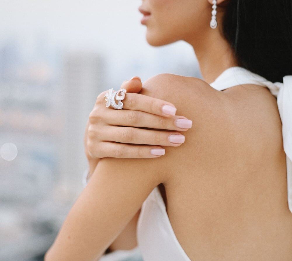 Baguette diamond ring and drop earring worn with a hand on the shoulder