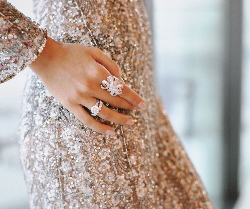 Diamond baguette cocktail ring and solitaire worn on one hand against a sequinned gown