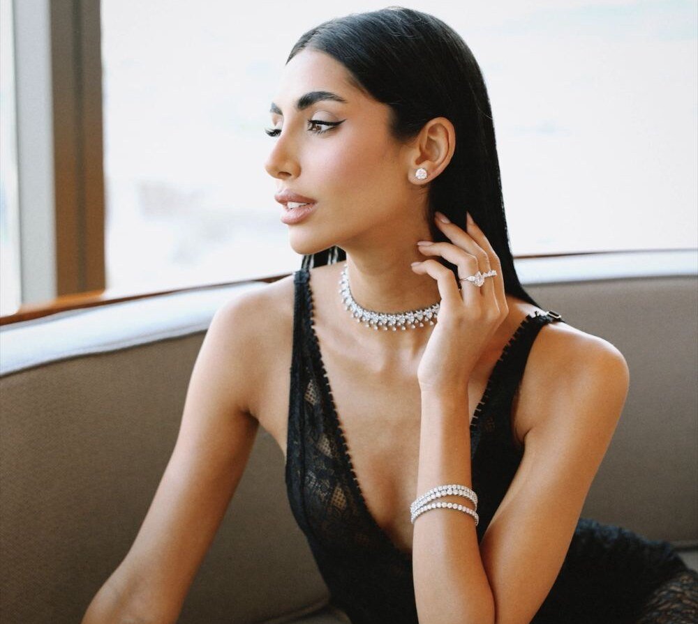 Model in black lace on a curved sofa wearing a diamond choker, studs and rings