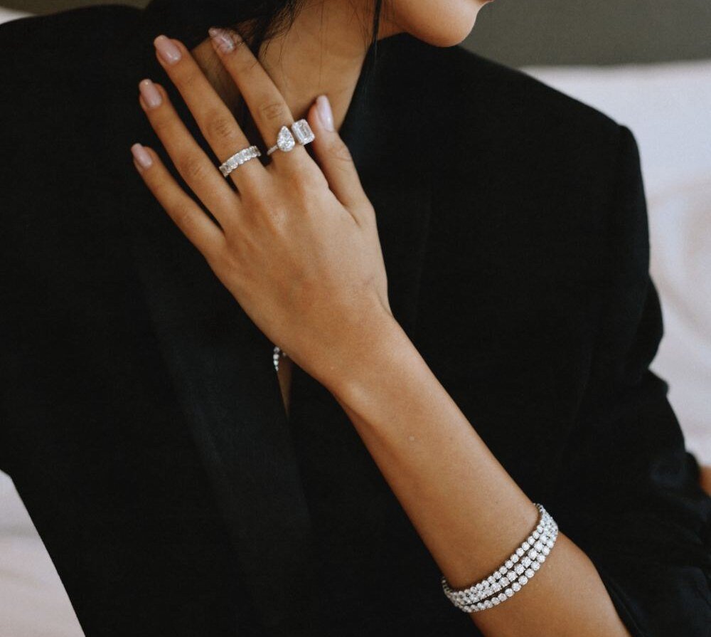 Diamond rings and tennis bracelet worn with a hand resting at the shoulder